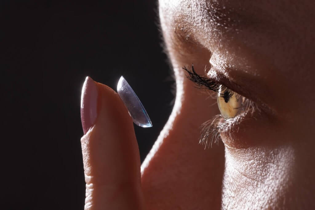 Frau gibt Kontaktlinse in Auge