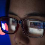 Mädchen mit Brille schaut auf einen Screen