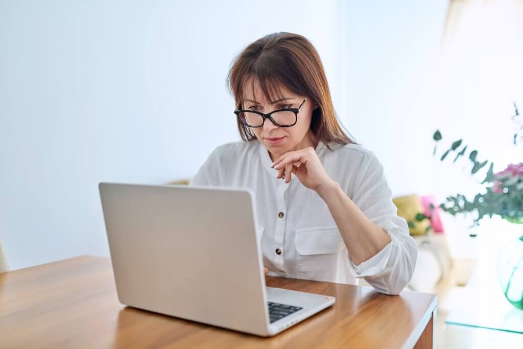 Frau sitzt vor Laptop und nimmt an Online Eignungstest fürs Augenlasern teil