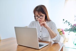 Frau sitzt vor Laptop und nimmt an Online Eignungstest fürs Augenlasern teil